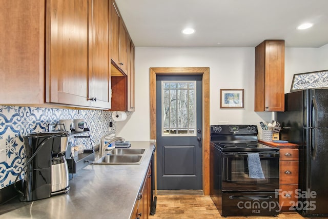 kitchen with stainless steel countertops, brown cabinets, a sink, black appliances, and backsplash