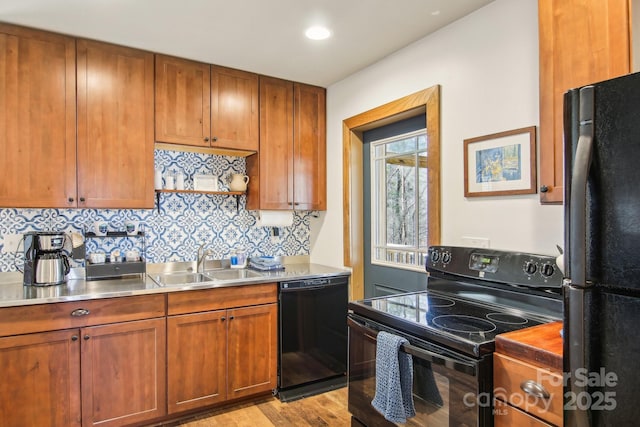 kitchen with a sink, light countertops, black appliances, tasteful backsplash, and brown cabinetry