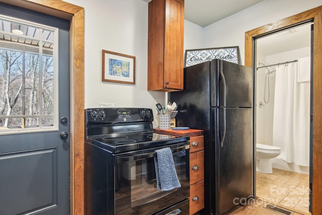 kitchen featuring black appliances, brown cabinetry, tile patterned flooring, and visible vents