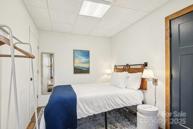 bedroom with a drop ceiling and wood finished floors