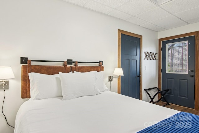 bedroom featuring a drop ceiling and wood finished floors