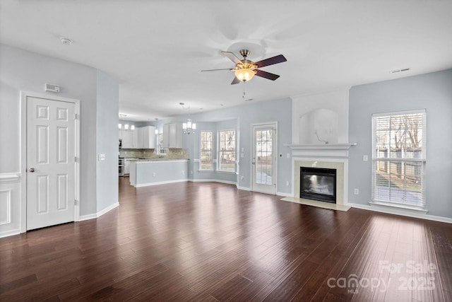 unfurnished living room with a premium fireplace, dark hardwood / wood-style flooring, and ceiling fan with notable chandelier