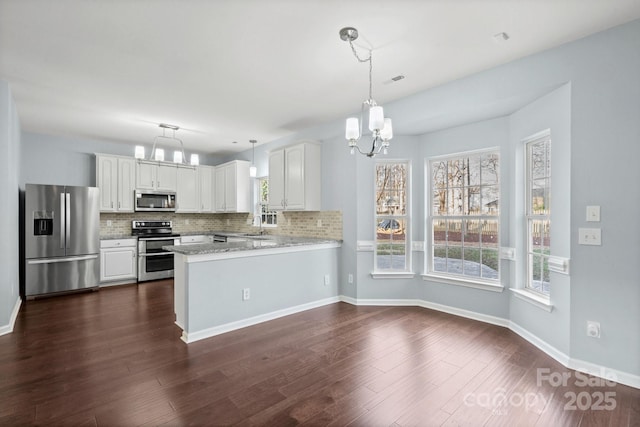 kitchen featuring pendant lighting, appliances with stainless steel finishes, a notable chandelier, white cabinets, and kitchen peninsula