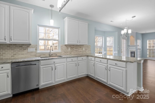 kitchen featuring sink, dishwasher, white cabinetry, hanging light fixtures, and kitchen peninsula