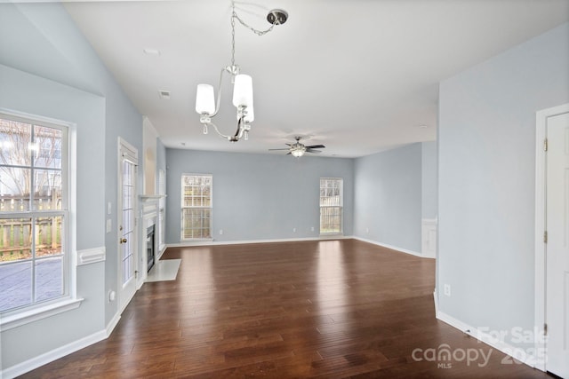 empty room featuring ceiling fan with notable chandelier and dark wood-type flooring