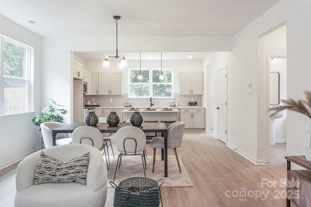 dining area featuring a notable chandelier, light hardwood / wood-style flooring, and sink