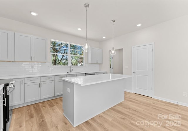 kitchen with light hardwood / wood-style flooring, hanging light fixtures, stainless steel range with electric stovetop, a kitchen island, and sink