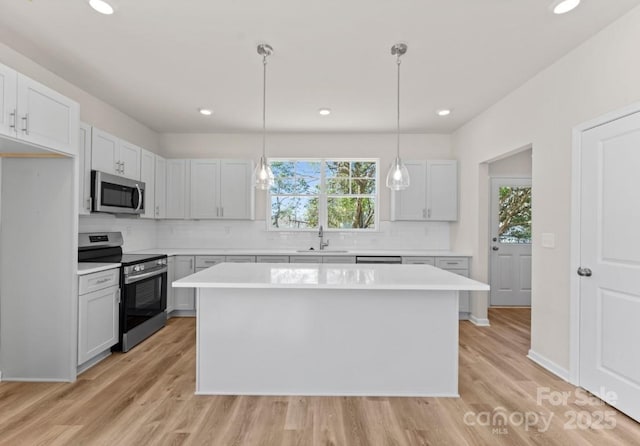 kitchen featuring light hardwood / wood-style flooring, stainless steel appliances, pendant lighting, a center island, and sink