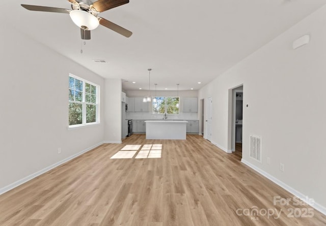 unfurnished living room with ceiling fan, sink, and light hardwood / wood-style floors