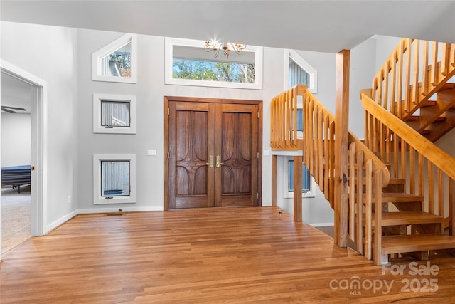 foyer with an inviting chandelier, a towering ceiling, and light wood-type flooring