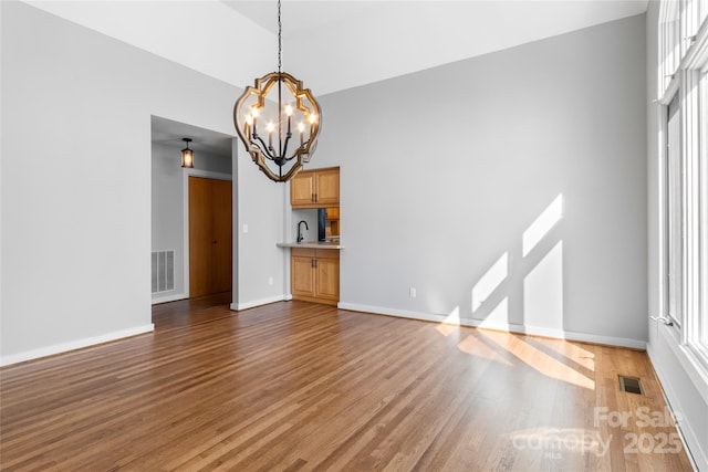 unfurnished living room featuring hardwood / wood-style flooring, sink, and a notable chandelier