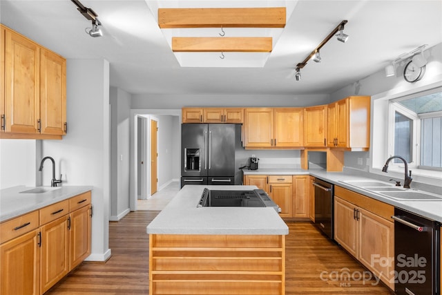 kitchen with dishwashing machine, sink, black refrigerator with ice dispenser, and a center island