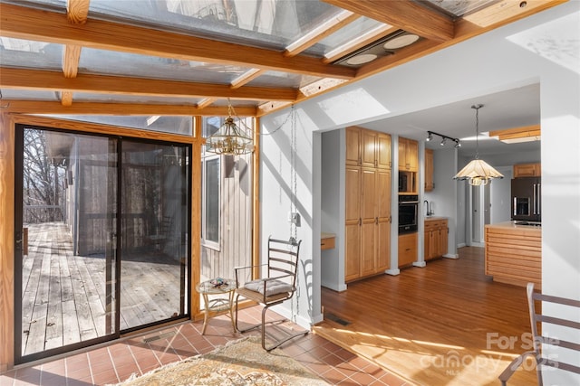 interior space featuring rail lighting, sink, an inviting chandelier, light hardwood / wood-style flooring, and beamed ceiling