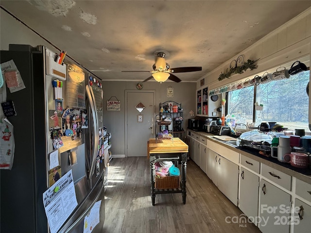 kitchen with stainless steel refrigerator with ice dispenser, ceiling fan, hardwood / wood-style flooring, and white cabinets