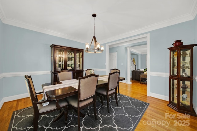 dining space with wood-type flooring, ornamental molding, and ornate columns