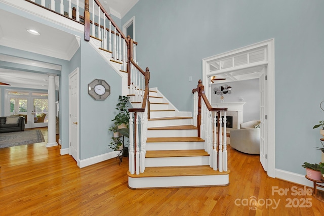 stairs with hardwood / wood-style floors, ornamental molding, and ornate columns