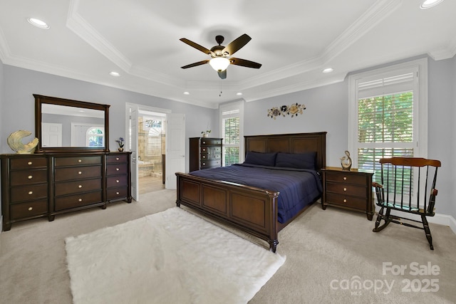 carpeted bedroom featuring a raised ceiling, ornamental molding, ensuite bathroom, and ceiling fan