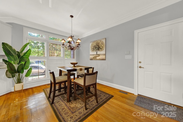 dining space featuring crown molding, a chandelier, and light wood-type flooring