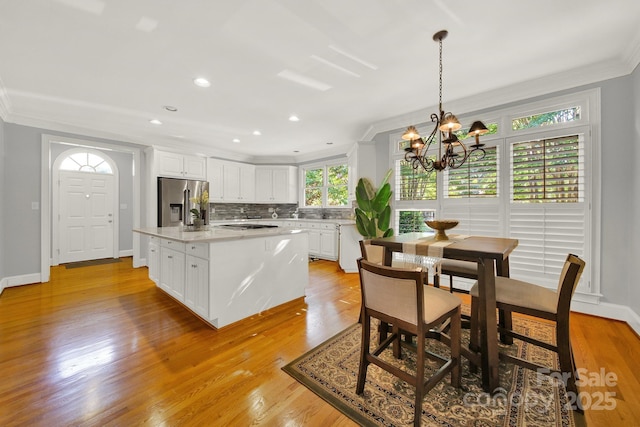 kitchen featuring pendant lighting, white cabinetry, backsplash, a center island, and stainless steel appliances