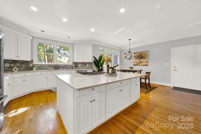 kitchen with a kitchen island, light wood-type flooring, hanging light fixtures, and white cabinets