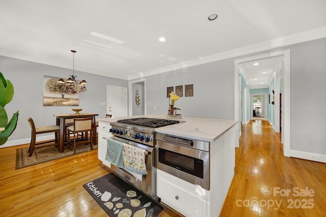 kitchen featuring decorative light fixtures, stainless steel appliances, light hardwood / wood-style floors, and white cabinets