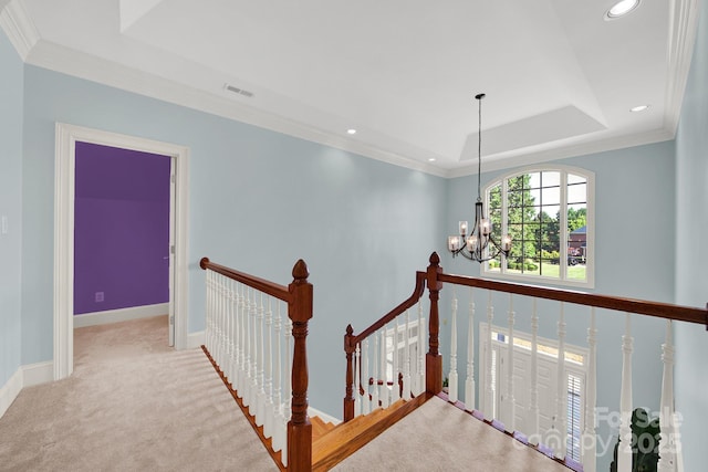 hall featuring ornamental molding, light colored carpet, a chandelier, and a tray ceiling