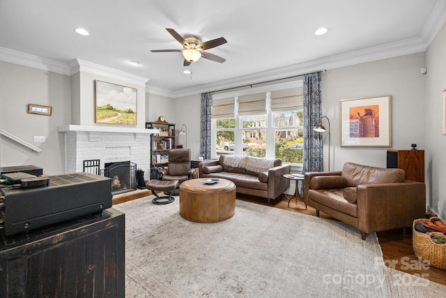 living room with ornamental molding, ceiling fan, a fireplace, and light wood-type flooring