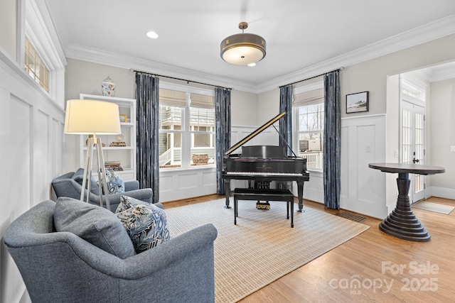 sitting room with ornamental molding and wood-type flooring