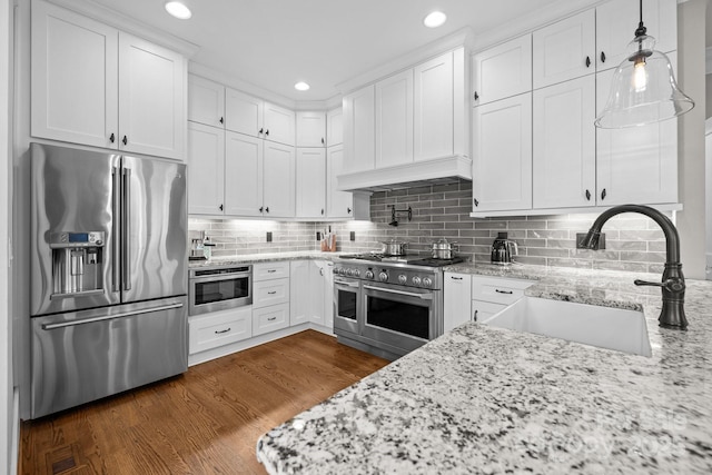 kitchen featuring sink, white cabinetry, pendant lighting, stainless steel appliances, and light stone countertops