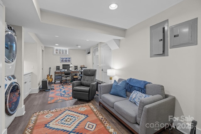 living room featuring stacked washer and dryer, dark wood-type flooring, and electric panel