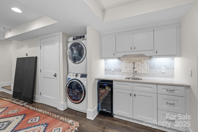 laundry area featuring stacked washing maching and dryer, dark hardwood / wood-style floors, wet bar, and wine cooler