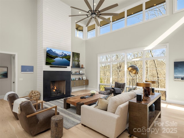 living room with a high ceiling, a large fireplace, and light hardwood / wood-style flooring