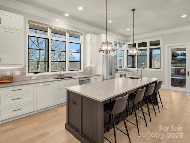 kitchen with stainless steel appliances, sink, an island with sink, and white cabinets