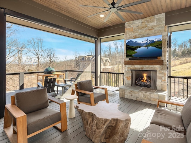 deck featuring ceiling fan and an outdoor stone fireplace