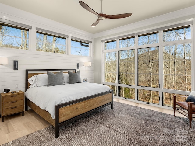 bedroom featuring ceiling fan, ornamental molding, and wood-type flooring