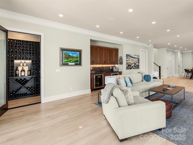 living room with ornamental molding, indoor bar, wine cooler, and light hardwood / wood-style floors