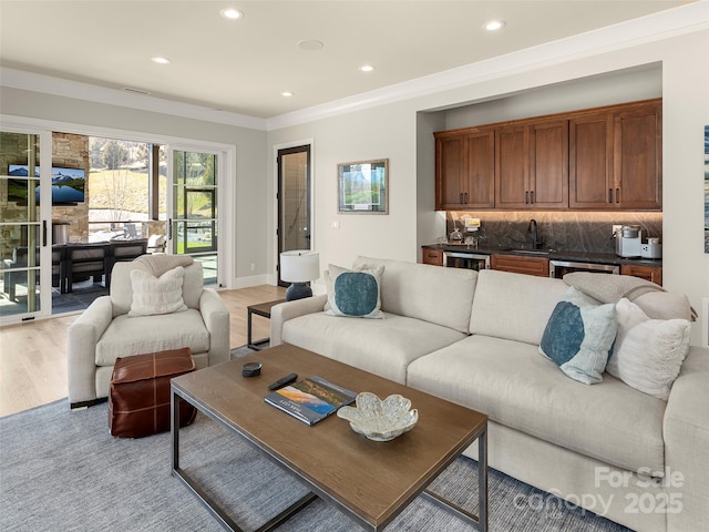 living room featuring crown molding, light hardwood / wood-style flooring, and wet bar