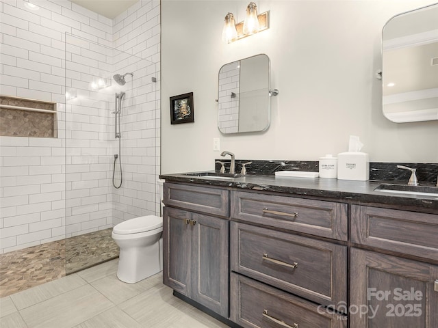 bathroom featuring vanity, toilet, and a tile shower