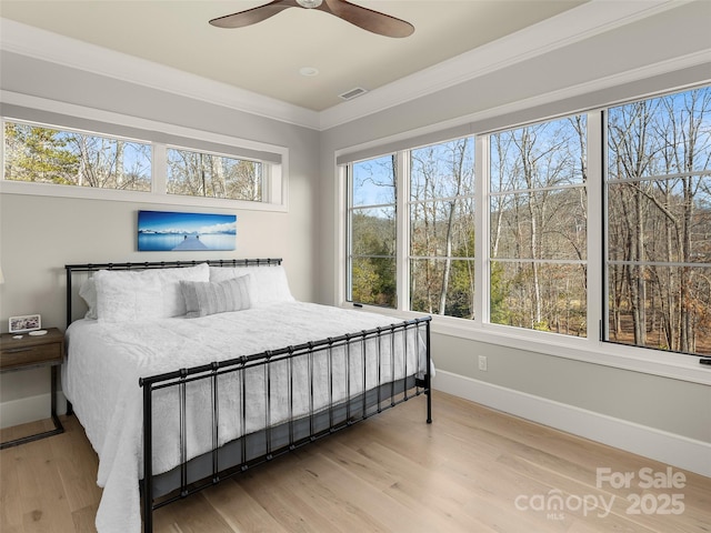 bedroom featuring crown molding, ceiling fan, hardwood / wood-style floors, and multiple windows