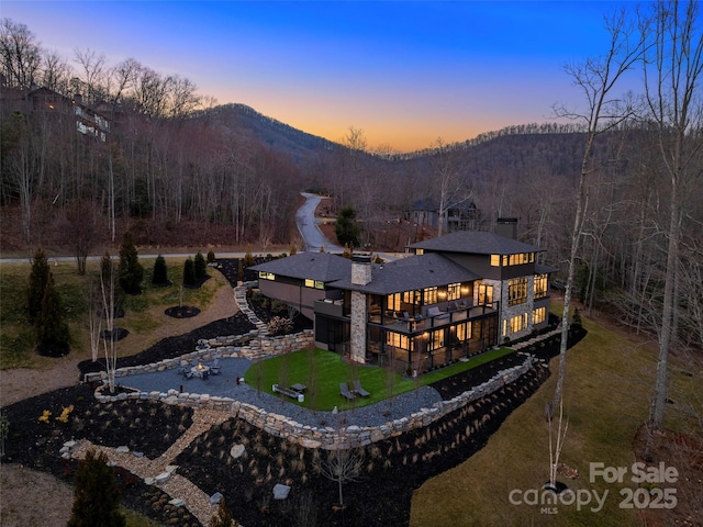 back house at dusk featuring a yard and a mountain view