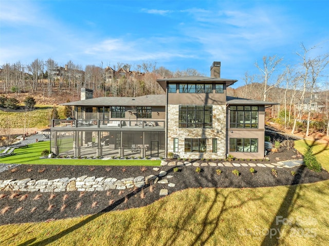 rear view of property with a balcony and a lawn