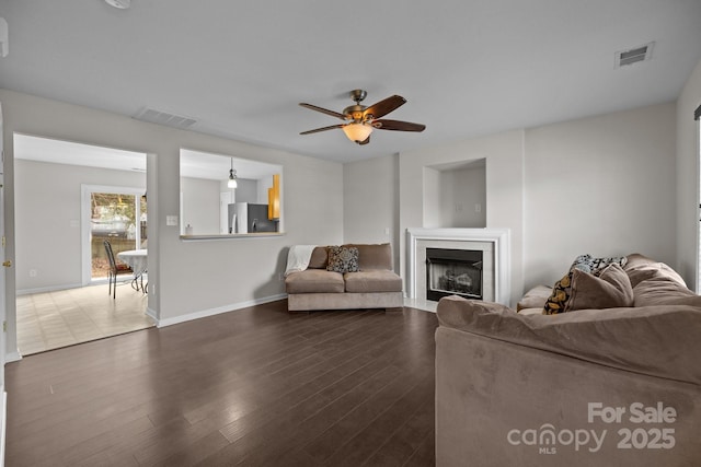 living room with a fireplace, visible vents, and dark wood-type flooring