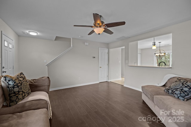 living area featuring ceiling fan with notable chandelier, dark wood finished floors, visible vents, and baseboards