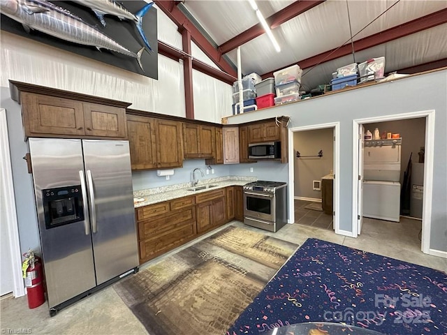 kitchen featuring high vaulted ceiling, appliances with stainless steel finishes, light stone countertops, and sink