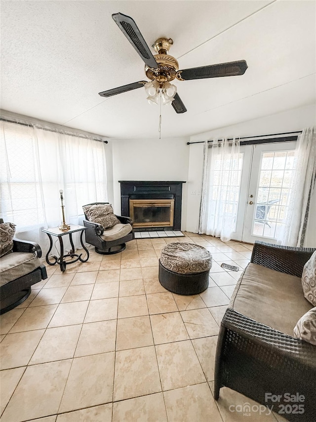 living room featuring ceiling fan, plenty of natural light, a textured ceiling, and light tile patterned floors