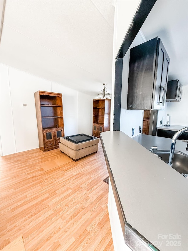 kitchen with lofted ceiling, sink, and light hardwood / wood-style flooring