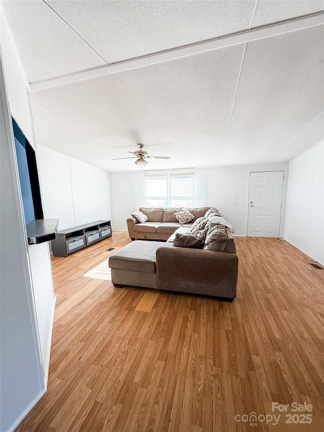 living room featuring ceiling fan, hardwood / wood-style floors, and a textured ceiling