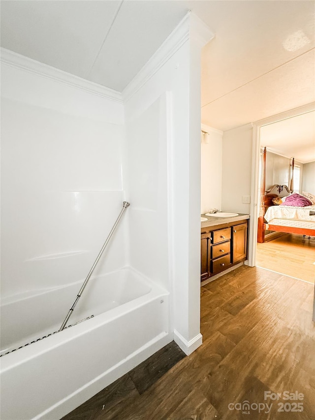 bathroom with crown molding, wood-type flooring, a bathtub, and vanity