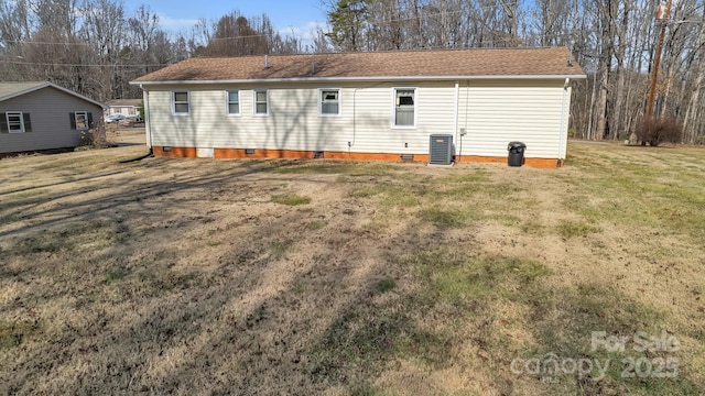 rear view of house with central AC and a lawn