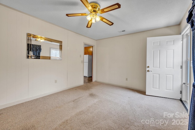 carpeted empty room featuring ceiling fan and a textured ceiling